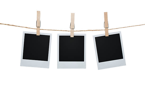 Three Polaroid pictures hanging on a clothesline with pins Blank photos hanging on a clothesline isolated on white background with clipping path for the inside of the frames clothespin photos stock pictures, royalty-free photos & images