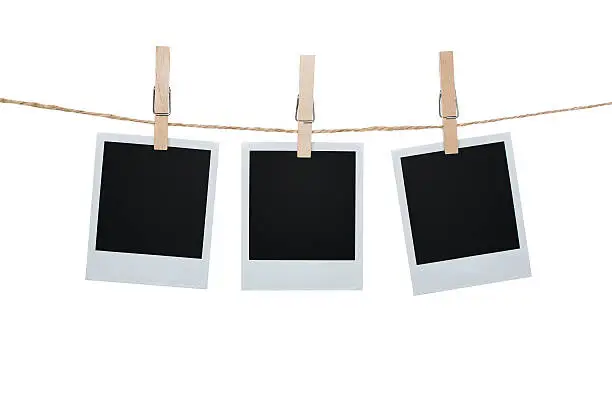 Blank photos hanging on a clothesline isolated on white background with clipping path for the inside of the frames