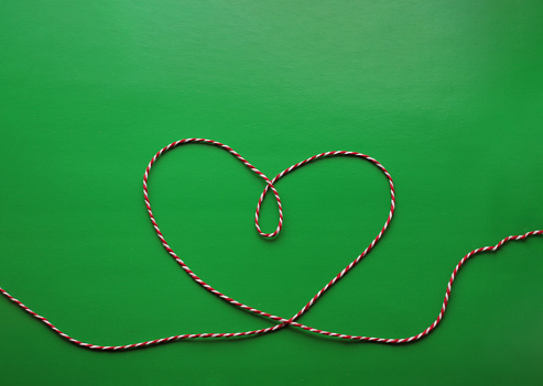 heart made of red and white thread on a green background