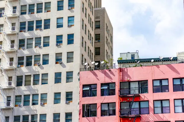 Satellite dishes on top of a pink apartment building in an urban city