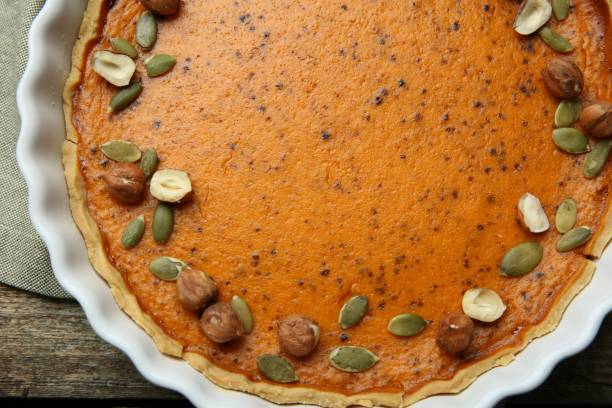deliziosa torta di zucca con semi e nocciole su tavolo di legno, vista dall'alto - healthy eating cake halloween seed foto e immagini stock