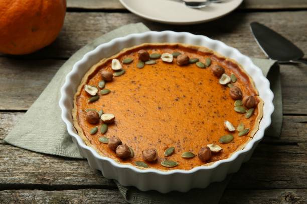 deliziosa torta di zucca con semi e nocciole su tavolo di legno - healthy eating cake halloween seed foto e immagini stock