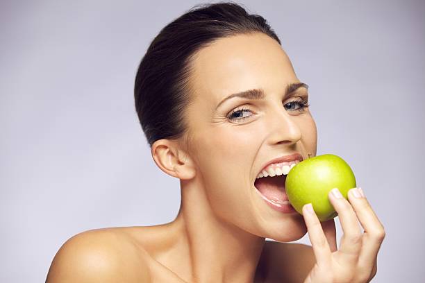 junge glückliche frau essen grüner apfel - sensuality women apple naked stock-fotos und bilder