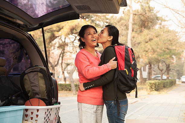 mãe e filha abraçar atrás de carro no campus universitário - twenty first imagens e fotografias de stock