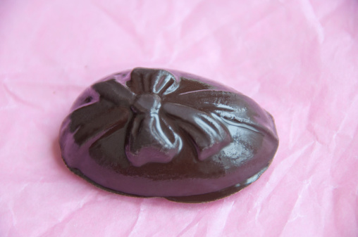 A peanut-butter filled chocolate Easter egg tempts diners on a piece of pink wrapping paper.