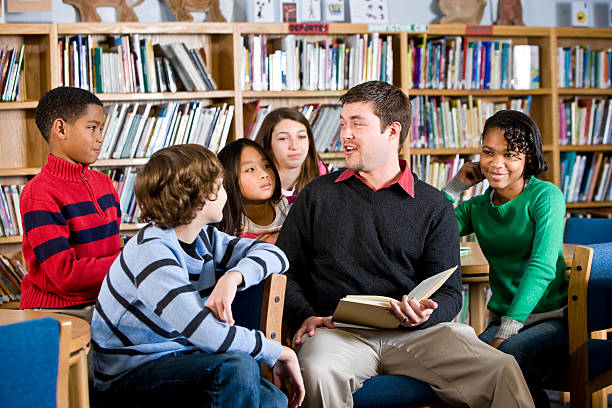 istock Teacher or librarian reading to group of children 183578819