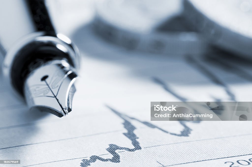 Fountain pen on graph in newspaper with coins Business Performance Graph with a Fountain Pen and coins Macrophotography Stock Photo