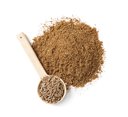 Heap of aromatic caraway (Persian cumin) powder and wooden spoon of seeds isolated on white, top view
