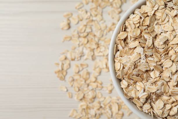 istock Bowl with oatmeal on white wooden table, top view. Space for text 1835797965