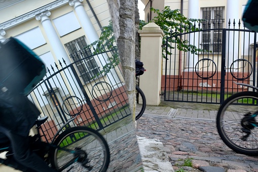 How many bikes? - Two bicycles on the image appear as three, as one of the bicycles is reflected in the mirror. One bicycle is going left, and one is going right (and reflected in the mirror standing on the left). The round wheels of the bicycles are additionally supplemented by the round patterns on the fence.