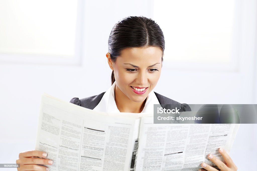 Business woman reads a newspaper. Young attractive business woman reads a newspaper. White background. Adult Stock Photo