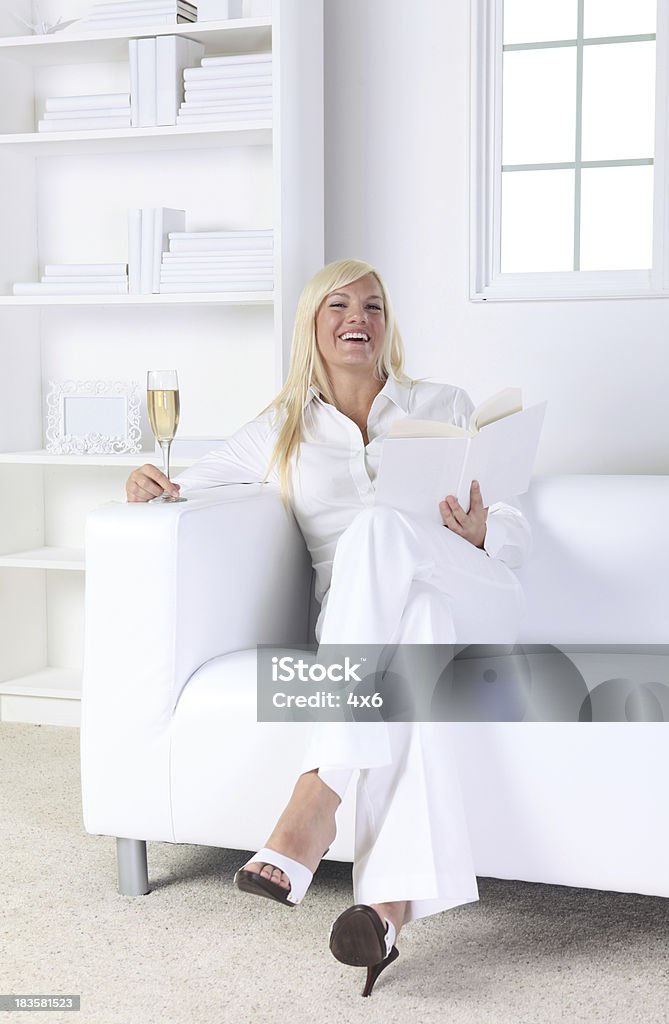 Lectura de mujer feliz en casa con una copa de vino - Foto de stock de Actividades recreativas libre de derechos