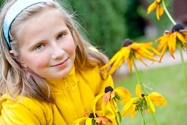 Happy little girl with braces in the garden in bushes of peonies, child with the flower, sunlight. Summer in the garden. Vacation in village.