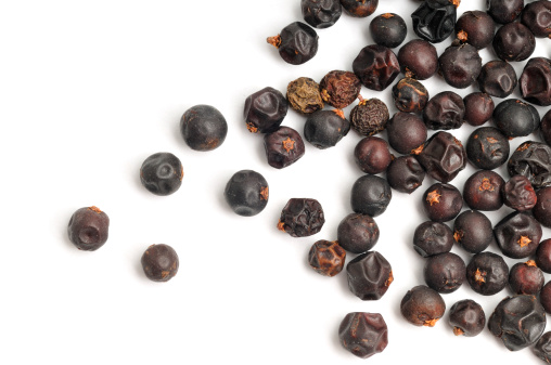 Dried Juniper berries scattered across a white background.