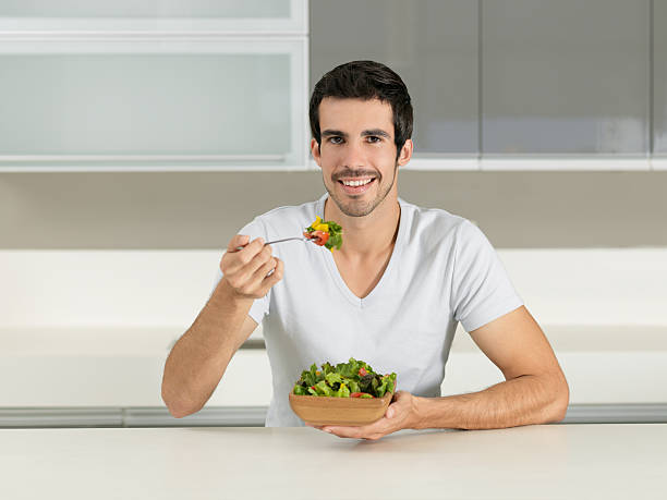 istock Young man eating a healthy salad 183582178