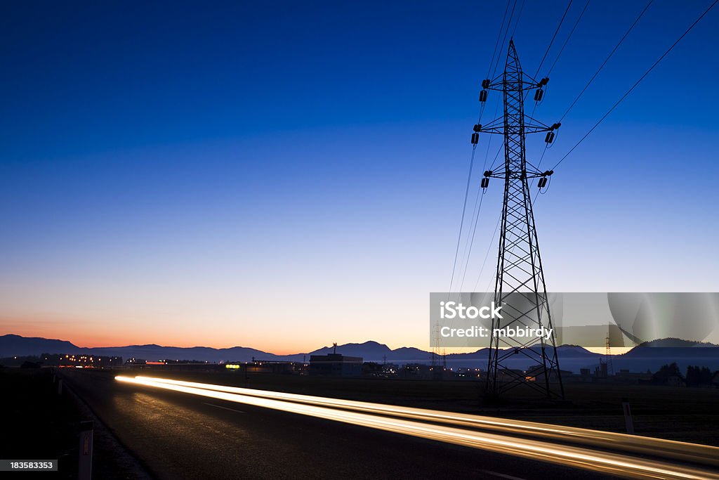 Electricity pylon at sunset "Electricity pylon at sunset, car passing by with tail light." Beauty In Nature Stock Photo