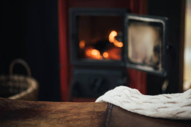Empty table with burning fireplace on the background in cozy log cabin. Place for text.