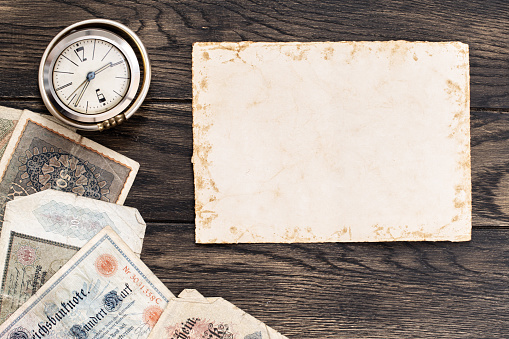 Old sheet of paper with obsolete european banknotes and vintage clock. Financial or numismatic concept