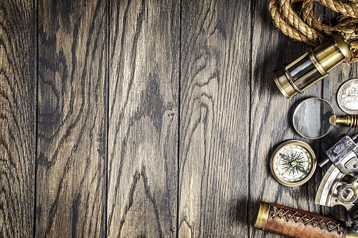 Medieval nautical instruments at right side of oak woodn table, top view with copy space