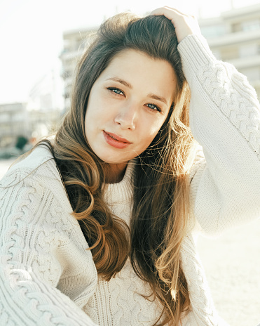Sunlit portrait of a woman in a cozy sweater, a look of contentment on her face