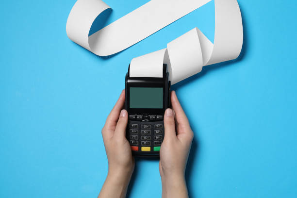 istock Woman using payment terminal with thermal paper for receipt on light blue background, top view 1835869768