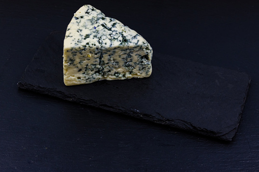 Piece of blue cheese with mold on slate board