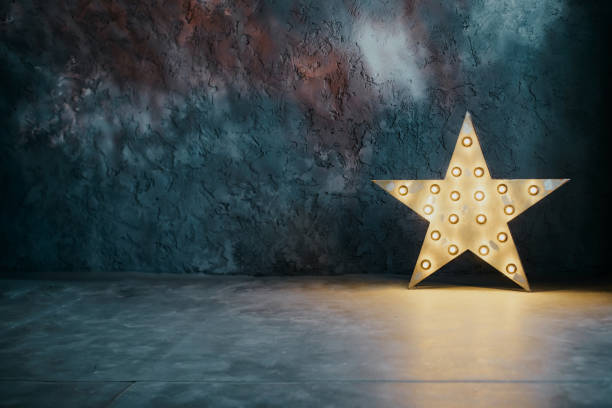 istock A star-shaped lamp on the floor against a blue textured wall. Background for custom design with space for text. New Year, Christmas, Birthday greeting card idea. 1835895353