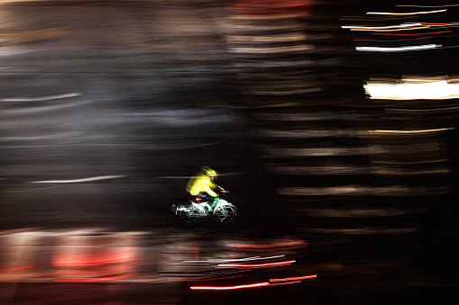 A lone rider, clad in a bright yellow jacket, cuts through the chaos of light streaks. Their motorcycle is a mere suggestion within the vibrant chaos, their destination unknown.