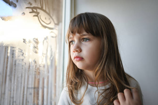 istock Pensive little girl looking throw window. 1835928379