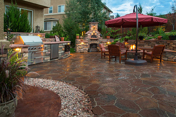 Beautiful Backyard Paver patio with a fire pit, outdoor kitchen, pizza oven and lighting at dusk. show garden stock pictures, royalty-free photos & images