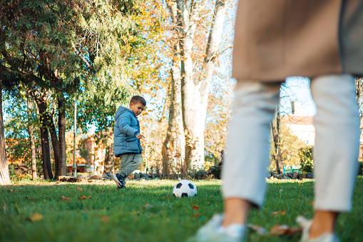 Full-length portrait of happy father, little boy and girl running and playing catch game in autumn park. Family, parenthood, leisure and people concept. Horizontal shot.