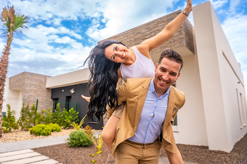 Happy woman piggybacking her couple celebrating to buy a new home