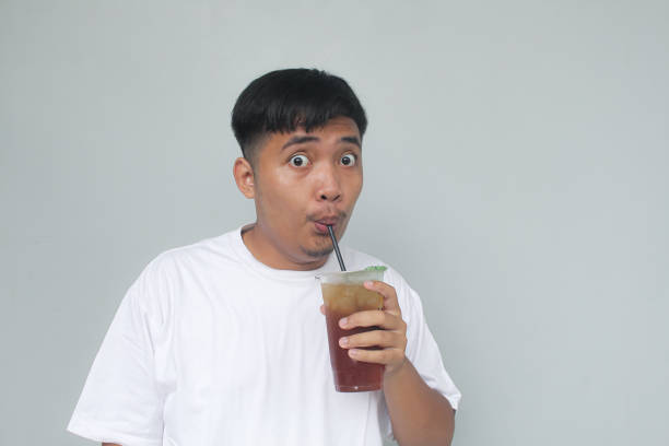 istock Young Asian man sucking iced tea with happy expression. 1835970912