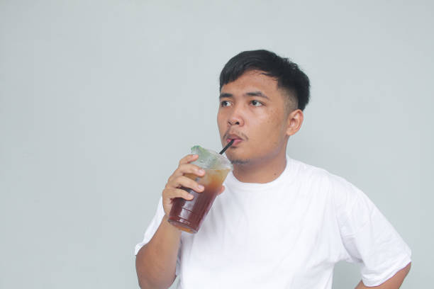 istock Young Asian man sucking iced tea with happy expression. 1835972953