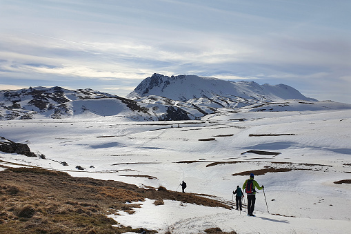 Three persons showshoeing towards Monte Morrone, a mountain of the Majella range, in Abruzzo region, Italy