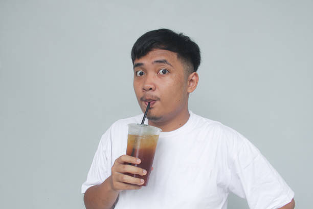 istock Young Asian man sucking iced tea with happy expression. 1835973470