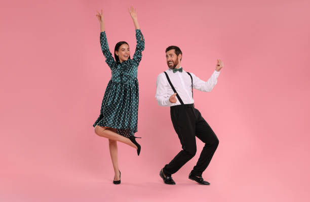 happy couple dancing together on pink background - polka dancing imagens e fotografias de stock