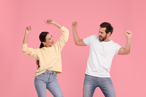 Happy couple dancing together on pink background