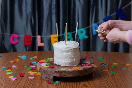 White Birthday cake with colorful Sprinkles and sparkler over a neutral background.