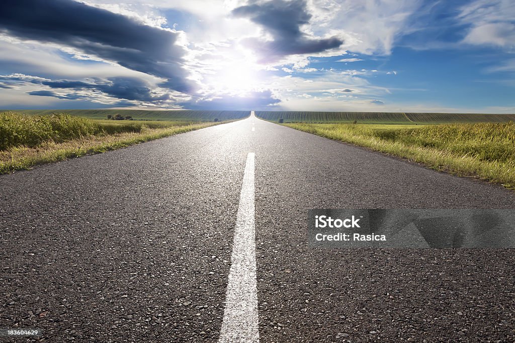 Empty road leading towards the sun Driving on an empty road to the sun Road Stock Photo