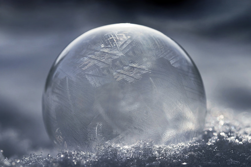 A frozen soap bubble with a pattern in the cold snow