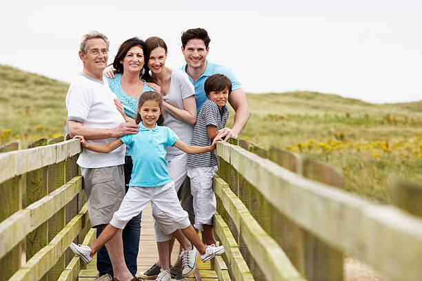 Family Portrait taken at a low angle on a bridge. They are wearing warm casual clothing and smiling.