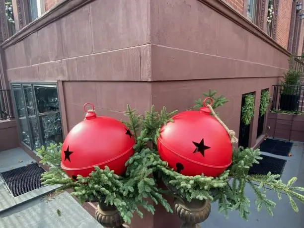 Photo of Giant red jingle bell decorations in front of a brownstone building in Harlem, New York City