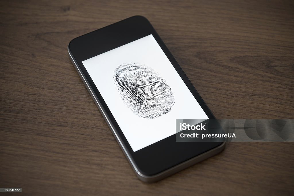 Mobile phone security concept Modern mobile phone with fingerprint mark on a screen lying on brown wooden desk. Mobile security concept. Accessibility Stock Photo