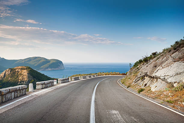 strada di montagna con cielo blu e mare su uno sfondo - horizon summer beach cliff foto e immagini stock