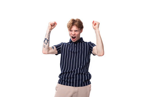joyful stylish young blond guy in a striped polo shirt with a tattoo on a white background.