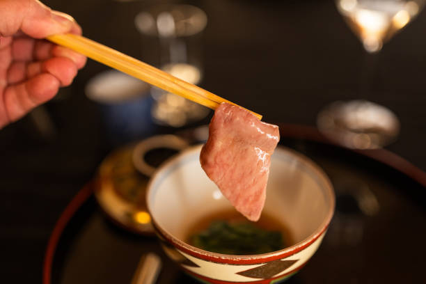 Picking up a slice of Sendai A5 beef with chopsticks at a high end Japanese restaurant.