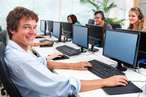 Portrait of smiling male student working on computer with mates.
