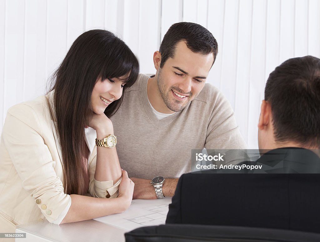 Happy Young Couple Discussing With Consultant Happy Young Couple Discussing With Consultant In Office Couple - Relationship Stock Photo