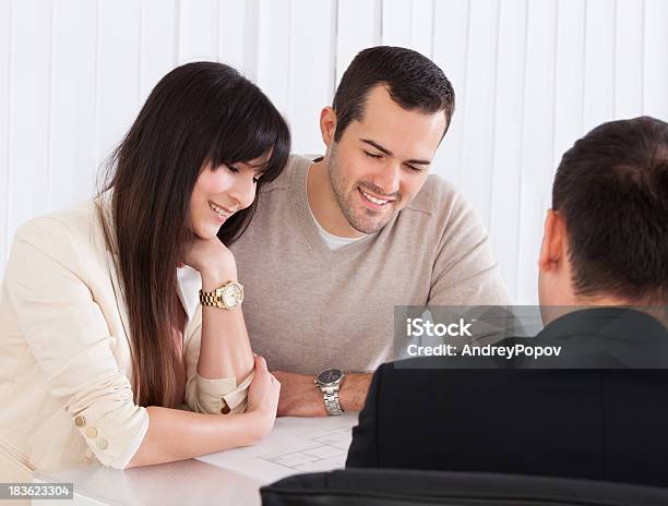 Happy Young Couple Discussing With Consultant Stock Photo - Download Image Now - Couple - Relationship, Discussion, Lawyer